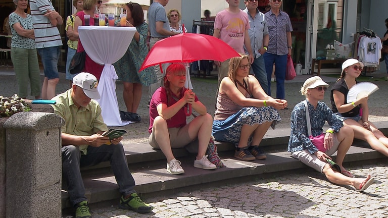 Menschen mit Sonnenschirm und Fächer, die sich vor der Hitze schützen (Foto: SWR)