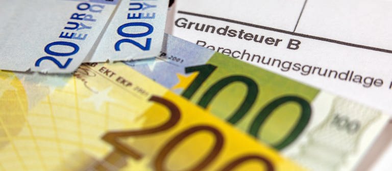 Geldscheine liegen auf einem Grundsteuer-Abgabenbescheid (Foto: picture-alliance / Reportdienste, picture alliance/dpa | Jens Büttner)