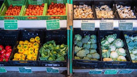 Boxen mit verschiedenen Gemüsen stehen auf einem Bioland-Hof zum Verkauf. In Hofläden und Bio-Supermärkten macht sich die Inflation bemerkbar. (Foto: picture-alliance / Reportdienste, picture alliance/dpa | Lino Mirgeler)