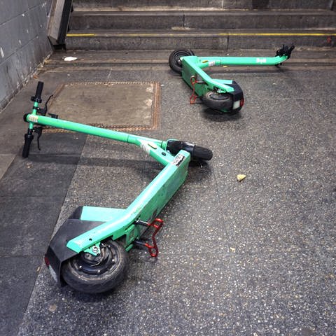Sogenannte E-Scooter, auch als Elektro-Tretroller bekannt, liegen umgestoßen an einem Treppenaufgang (Foto: IMAGO, IMAGO / Gottfried Czepluch)
