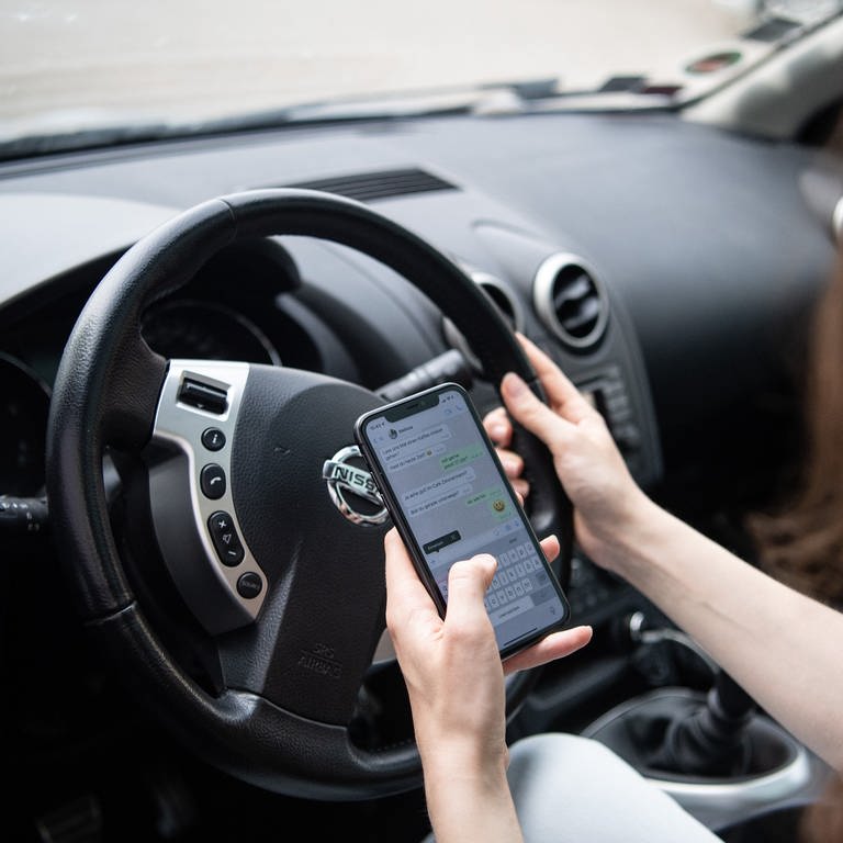 Eine Autofahrerin hat während der Fahrt ihr Handy in der Hand (Foto: dpa Bildfunk, picture alliance/dpa | Melissa Erichsen)