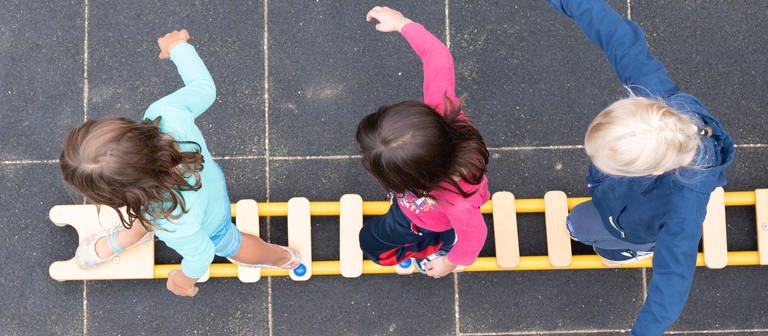 Kinder balancieren während eines Pressetermins auf dem Spielplatz einer Kindertagesstätte auf einem Brett. (Foto: picture-alliance / Reportdienste, picture alliance/dpa/dpa-Zentralbild | Sebastian Kahnert)