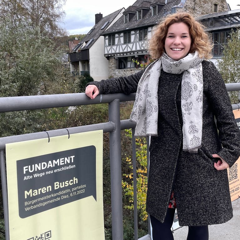Maren Busch steht auf der alten Lahnbrücke in Diez neben einem ihrer Wahlplakate. (Foto: SWR)