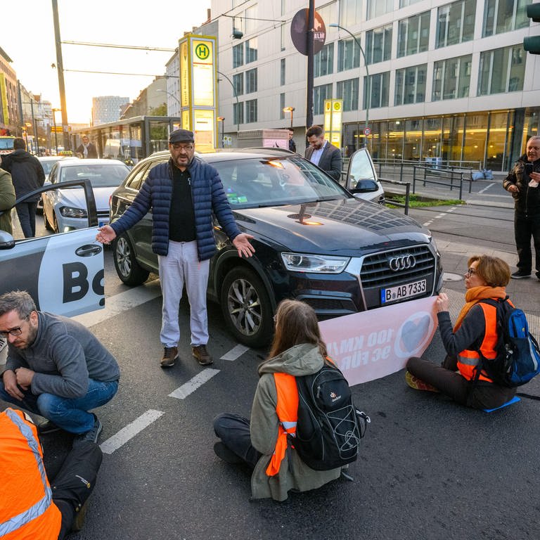 Aktivistin sitzen auf einer Straße und blockieren sie für Autofahrer. Die Autofahrer diskutieren mit den Aktivisten der "letzten Generation".  (Foto: picture-alliance / Reportdienste, picture alliance / PIC ONE | Stefan Müller)