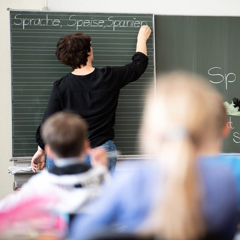 Eine Lehrerin schreibt in einer Grundschule Wörter mit "Sp" am Anfang an eine Tafel.  (Foto: dpa Bildfunk, Picture Alliance)