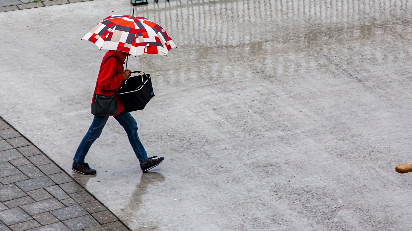 Menschen gehen mit einem Regenschirm bei Regen.