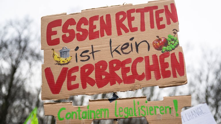 Plakat bei einer Demonstration mit der Aufschrift «Essen retten ist kein Verbrechen - Containern legalisieren!». (Foto: dpa Bildfunk, picture alliance/dpa | Christophe Gateau)