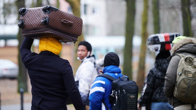 Flüchtlinge tragen ihre Koffer auf dem Kopf während sie ins Ankunftszentrum Reinickendorf gehen.  (Foto: dpa Bildfunk, Picture Alliance)