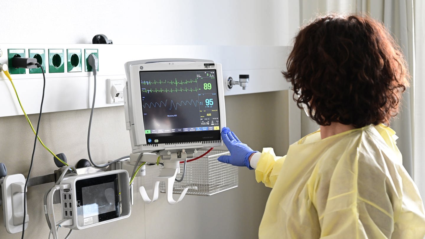 Eine Pflegerin schaut in einem Krankenzimmer im Klinikum Stuttgart auf einen Monitor einer Patientin. (Foto: dpa Bildfunk, picture alliance, Bernd Weißbrod)