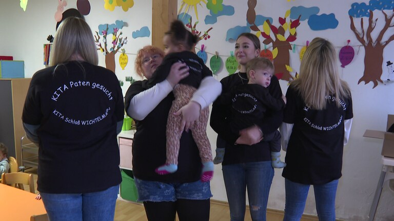 Erzieherinnen und Kinder der Kita Schloß Wichtelmann in Otterbach stellen T-Shirts "Kita Paten gesucht" vor (Foto: SWR)
