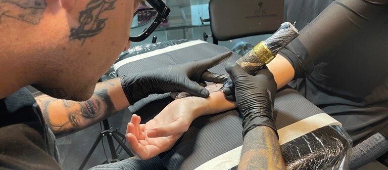 Ein Tattoo-Artist sticht seiner Kundin das Organspendetattoo. (Foto: SWR)