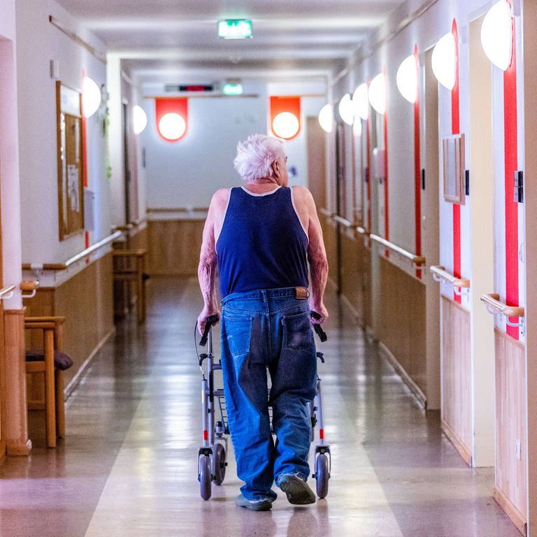 Pflegebedürftiger Senior im Altenheim schiebt Rollator durch einen leeren Flur (Foto: dpa Bildfunk, picture alliance/dpa | Jens Büttner)