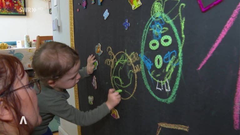 Kind malt mit bunter Kreide auf eine Tafel (Foto: SWR, SWR)