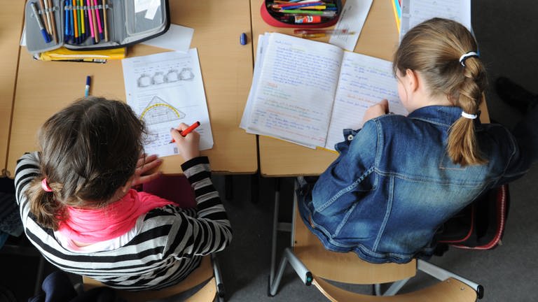 Zwei Schülerinnen einer 5. Klasse schreiben in ihre Hefte (Archivbild). (Foto: dpa Bildfunk, picture alliance / dpa | Daniel Bockwoldt)