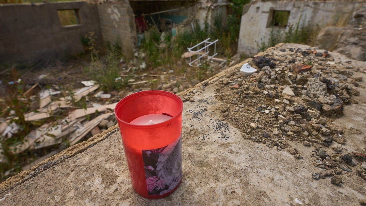 Eine Kerze auf den Grundmauern eines zerstörten Hauses erinnert an Todesopfer der Flutkatastrophe an der Ahr. (Foto: dpa Bildfunk, Picture Alliance)