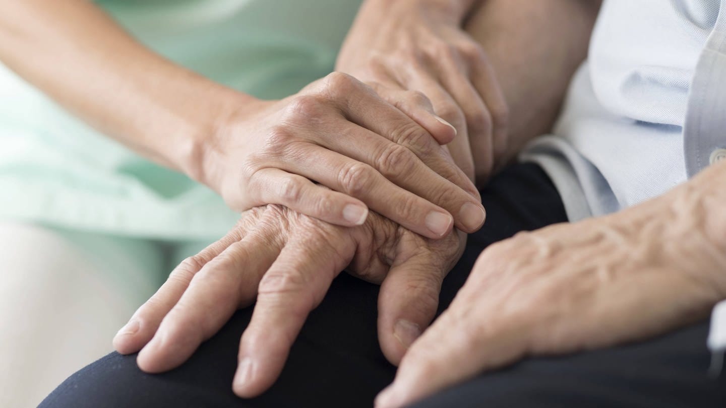 Ältere Hand wird von zwei jüngeren Händen einfühlsam gehalten (Foto: IMAGO, Science Photo Library)