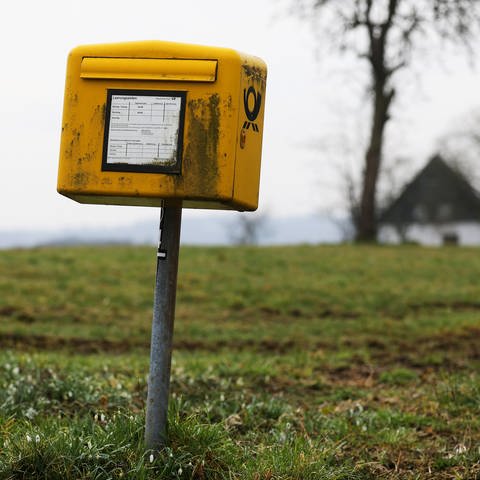 Ein verdreckter Briefkasten auf einer Wiese. (Foto: dpa Bildfunk, Picture Alliance)