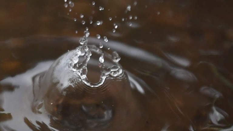 Wasser spritzt bei einem heftigen Regen nach dem Einschlag der Regentropfen in einer Pfütze in die Höhe (Foto: dpa Bildfunk, Picture Alliance)