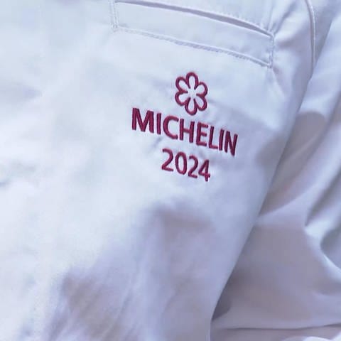 Koch mit einem Michelin-Abzeichen auf der Brust.