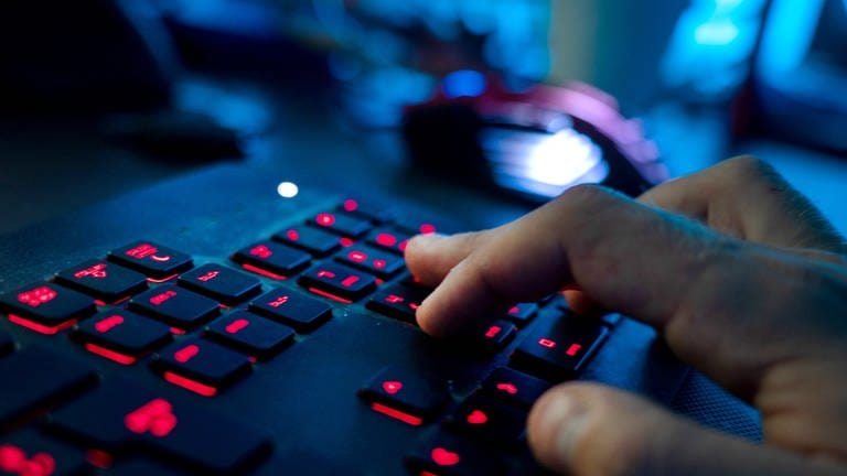Ein Mann sitzt am Rechner und tippt auf einer Tastatur. Kriminelle Hacker haben Unternehmen und öffentliche Einrichtungen im Visier und drohen oft damit, auch die Daten von unbeteiligten Kunden zu veröffentlichen.