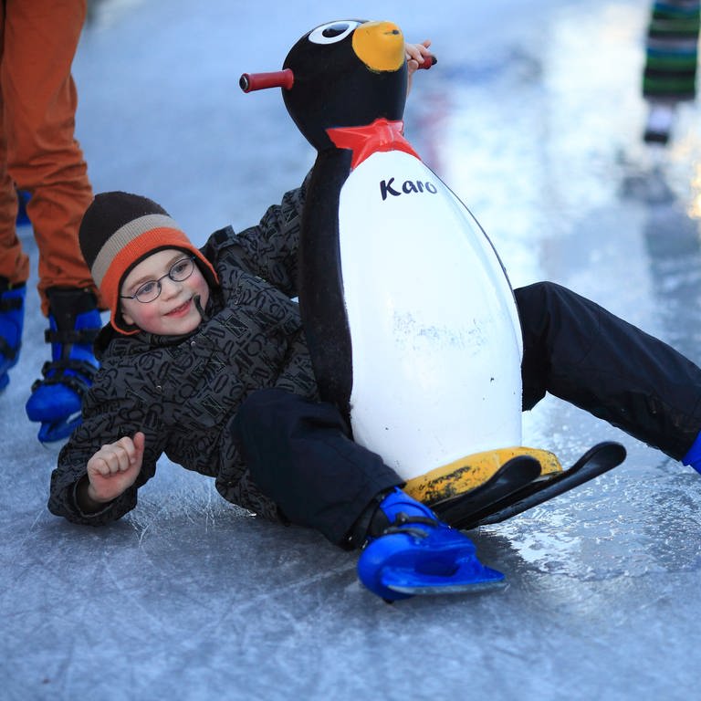 Kind mit einer Pinguinfigur beim Eislaufen. In Rheinland-Pflaz öffnen jetzt die Outdoor-Eisbahnen (Foto: dpa Bildfunk, Picture Alliance)