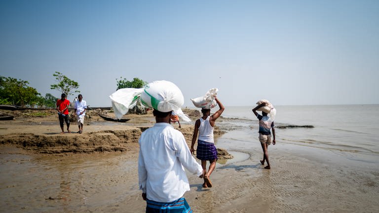 Menschen tragen Säcke in einer Region in Bangladesch, die von einem Zyklon getroffen wurde.