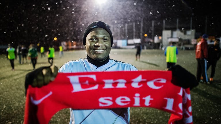 Ein junger Mann hält in Mainz  einen "Enten-Schal" in den Händen. Der Fußballverein "FC Ente Bagdad" versucht, durch Sport junge Flüchtlinge in Deutschland zu integrieren und wurde dafür jetzt mit dem Brückenpreis des Landes Rheinland-Pfalz ausgezeichnet.