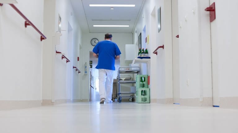 Ein Krankenpfleger geht über einen Flur im Krankenhaus 
