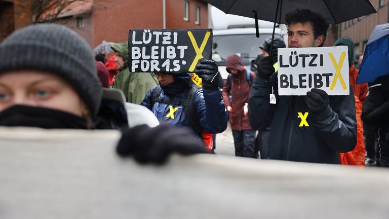 "Lützi bleibt" ist auf den Schildern zu lesen, die von Demonstranten getragen werden. (Foto: dpa Bildfunk, Picture Alliance)