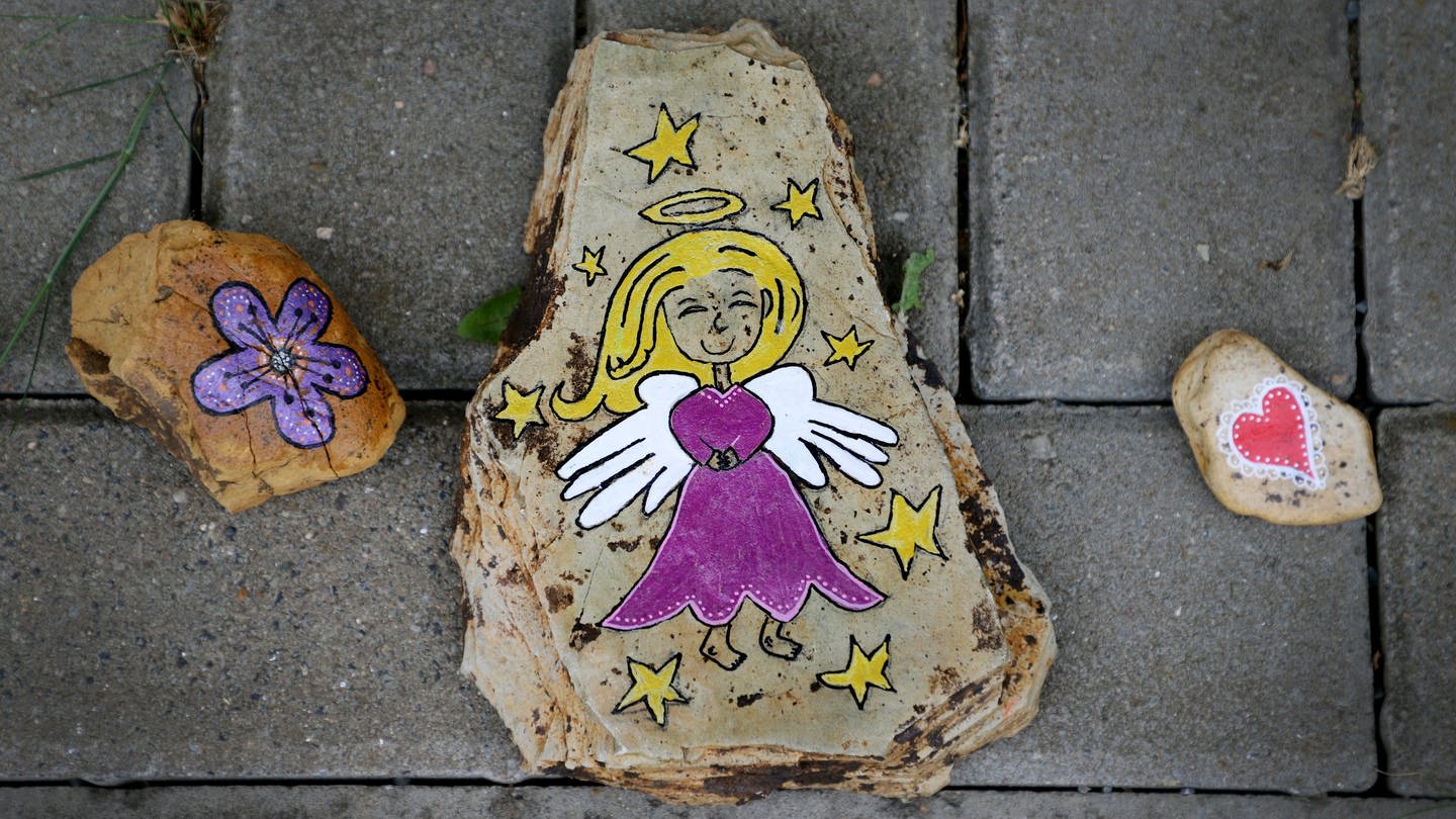 Ein mit einem Engel bemalter Stein liegt auf dem Boden (Foto: dpa Bildfunk, Picture Alliance)