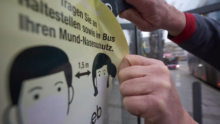 Ein Mitarbeiter der Koblenzer Verkehrsbetriebe entfernt an einer Haltestelle einen Aufkleber, der die Fahrgäste zum Tragen von Masken auffordert.  (Foto: picture-alliance / Reportdienste, picture alliance/dpa | Thomas Frey)