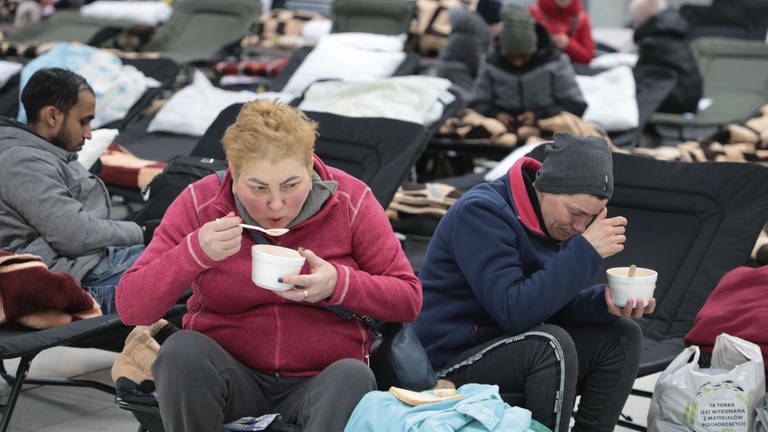 Flüchtlinge essen in einer Notunterkunft.