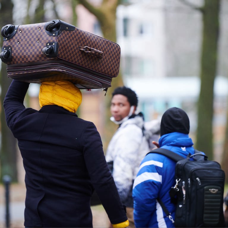 Flüchtlinge tragen ihre Koffer auf dem Kopf während sie ins Ankunftszentrum Reinickendorf gehen. 
