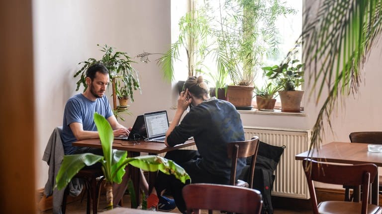 Zwei Männer sitzen in einem Co-Working-Space am Laptop und arbeiten.
