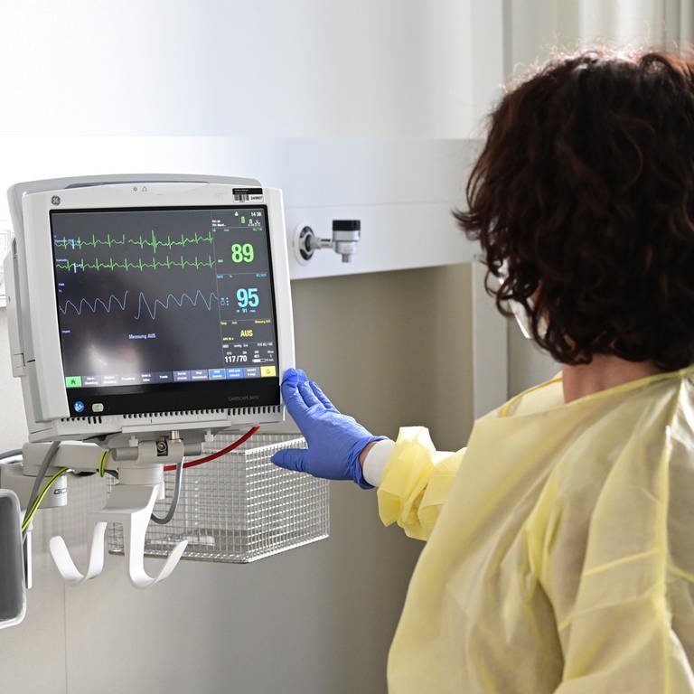 Eine Pflegerin schaut in einem Krankenzimmer im Klinikum Stuttgart auf einen Monitor einer Patientin. 