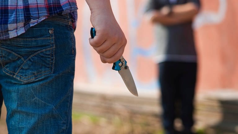 Ein Junge wird vor einem Jugendlichen mit einem Messer bedroht