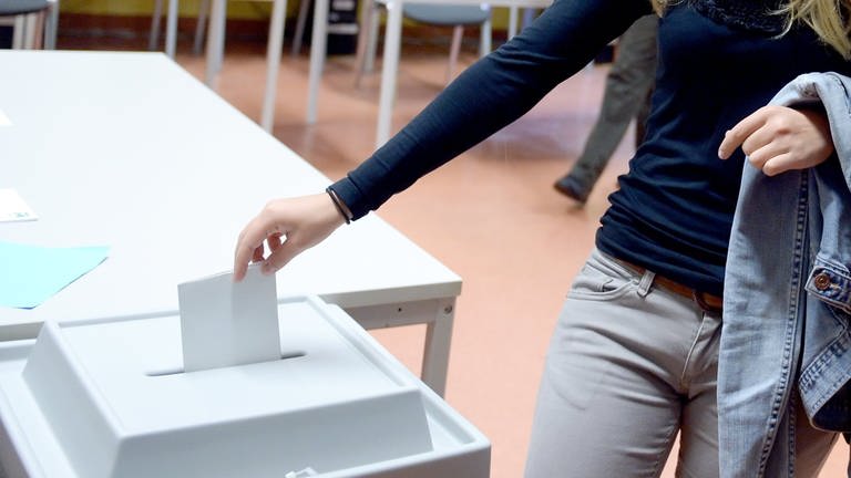 Eine Erstwählerin wirft einen Wahlzettel in eine Wahlurne.