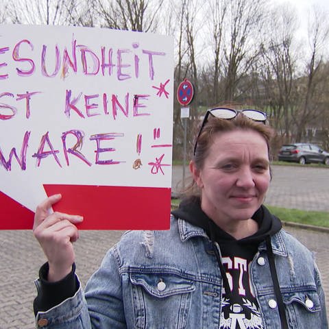 Frau hält Demoschild mit Aufschrift: 'Gesundheit ist keine Ware' hoch (Foto: SWR, SWR)