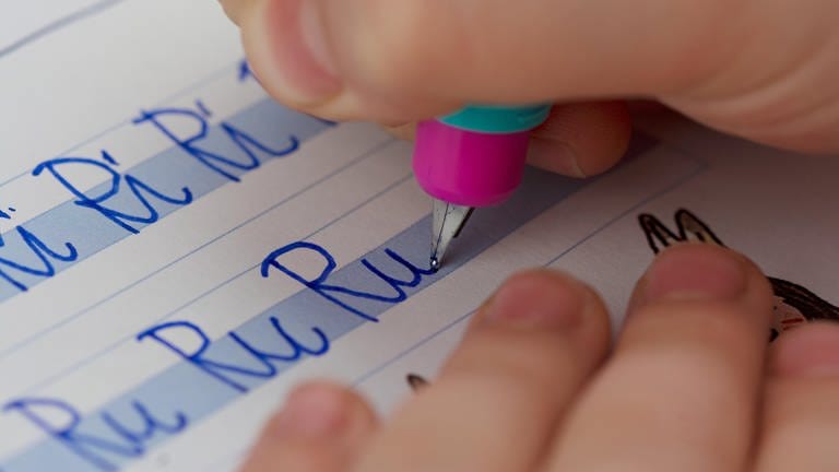 Nahaufnahme von Kinderhand mit Füller bei Schreibübung