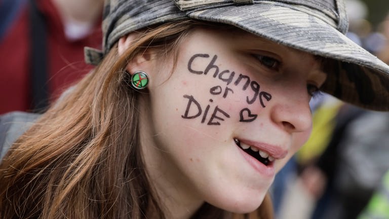 Gegen Klimawandel: Auf der Wange einer Demonstrantin steht "Change or DIE" (verändere oder sterbe).