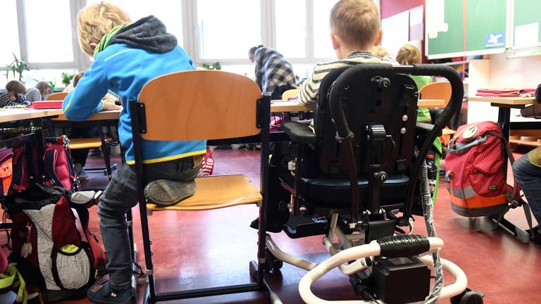 Behindertes und nicht behindertes Kind im Klassenzimmern an einem Tisch
