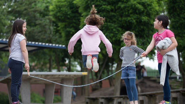 Schülerinnen springen Seil auf dem Pausenhof einer Grundschule 