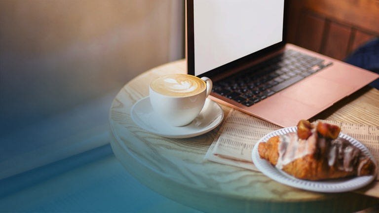 Ein Croissant und ein Café stehen auf einem Tisch vor einem Laptop (Foto: dpa Bildfunk, Picture Alliance)