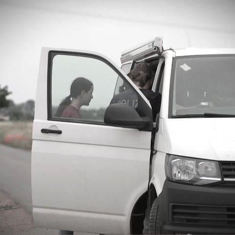 Polizei und eine Frau untersuchen einen weißen Van