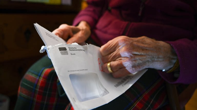 Eine alte Frau öffnet einen Brief der Deutschen Rentenversicherung. (Foto: dpa Bildfunk, Picture Alliance)