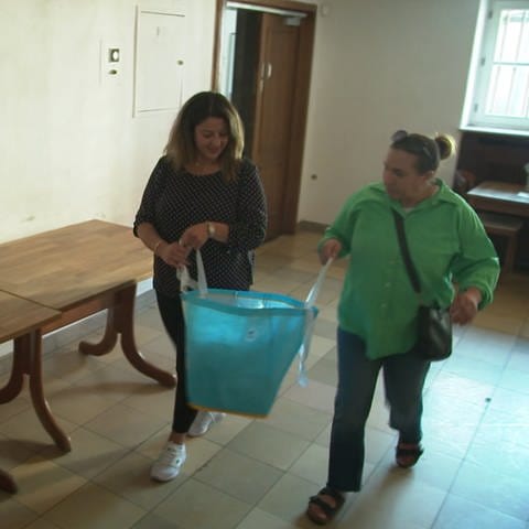 Zwei Frauen tragen eine Tüte mit medizinischen Hilfsmitteln für Erdbebenopfer in Marokko