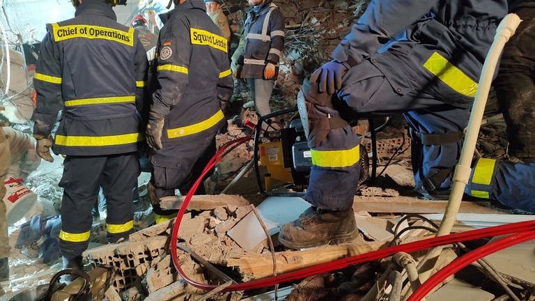 Einsatzkräfte des Technischen Hilfswerks (THW) stehen in den Trümmern eines eingestürzten Gebäudes nach dem Erdbeben im Februar 2023 in der Türkei.