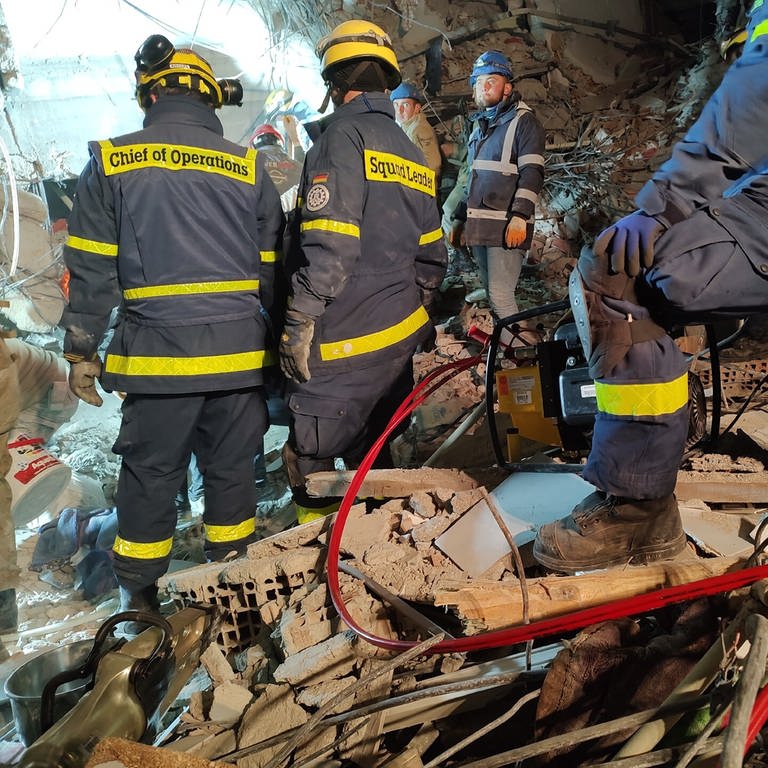 Einsatzkräfte des Technischen Hilfswerks (THW) stehen in den Trümmern eines eingestürzten Gebäudes nach dem Erdbeben im Februar 2023 in der Türkei.