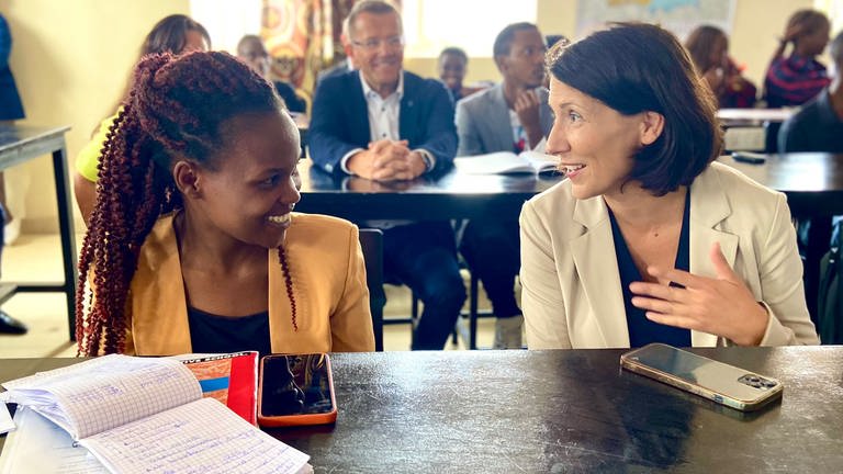Wirtschaftsministerin Daniela Schmitt sitzt neben einer jungen Frau aus Ruanda, die einen Deutsch-Kurs besucht. 