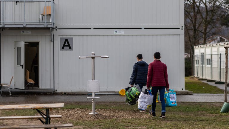 Symbolbild: Zwei Männner betreten eine Containerunterkunft